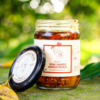 Open jar of Bhatt’s Ring Shaped Mango Pickle with its lid resting beside it outdoors.