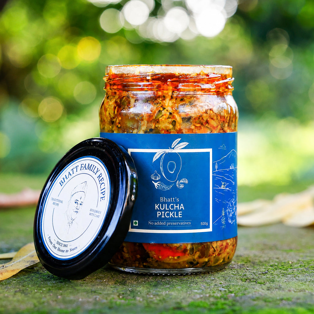 Open jar of Bhatt’s Kulcha Pickle with its blue label and lid resting beside it outdoors.