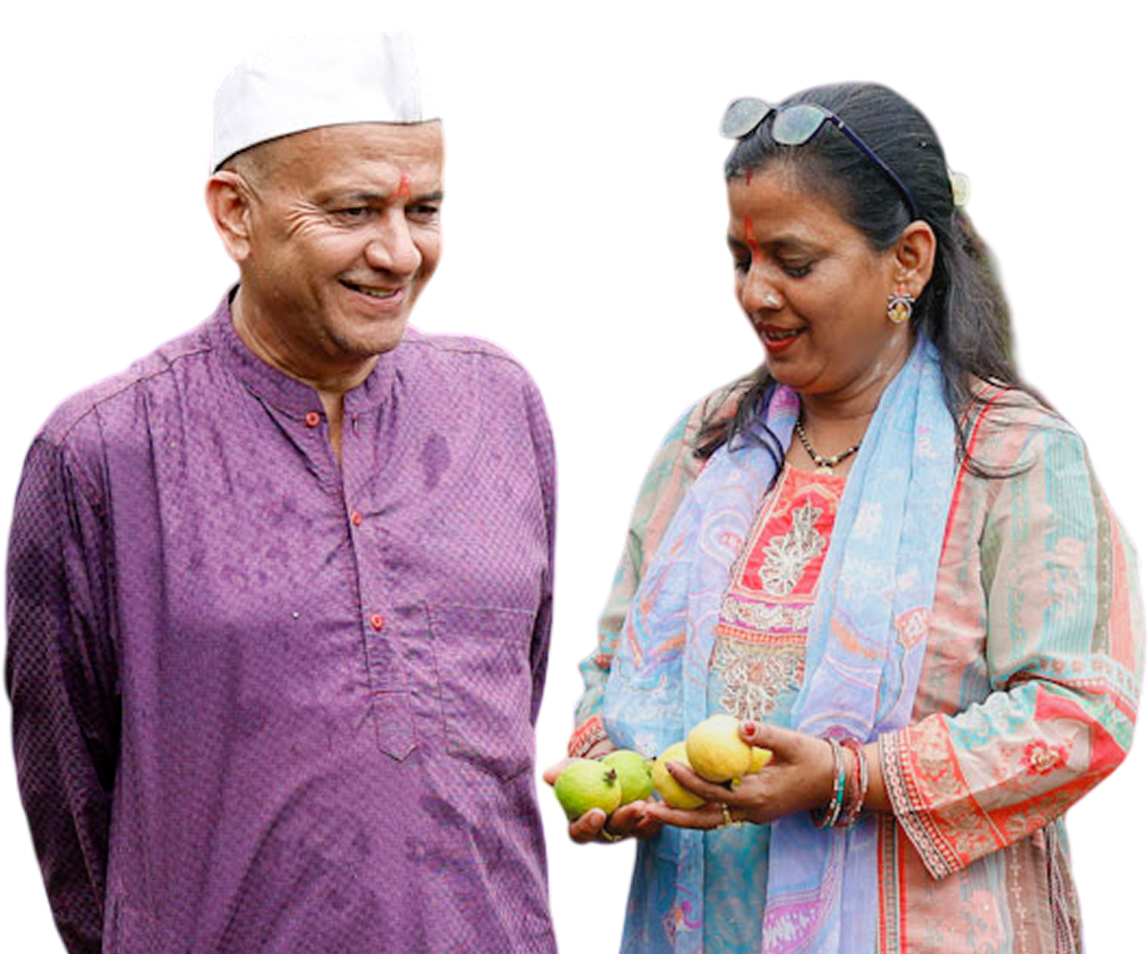 A man in a purple kurta and white cap smiling next to a woman in a colorful patterned outfit holding green and yellow fruits, isolated on a white background.