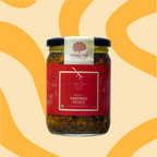 A glass jar of Mahalaxmi Bhatt's Karonda Pickle with a red label and black lid, set against a warm beige background with yellow wavy patterns.