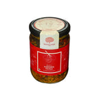 A glass jar of Karonda Pickle with a red label and black lid, set against a plain white background.